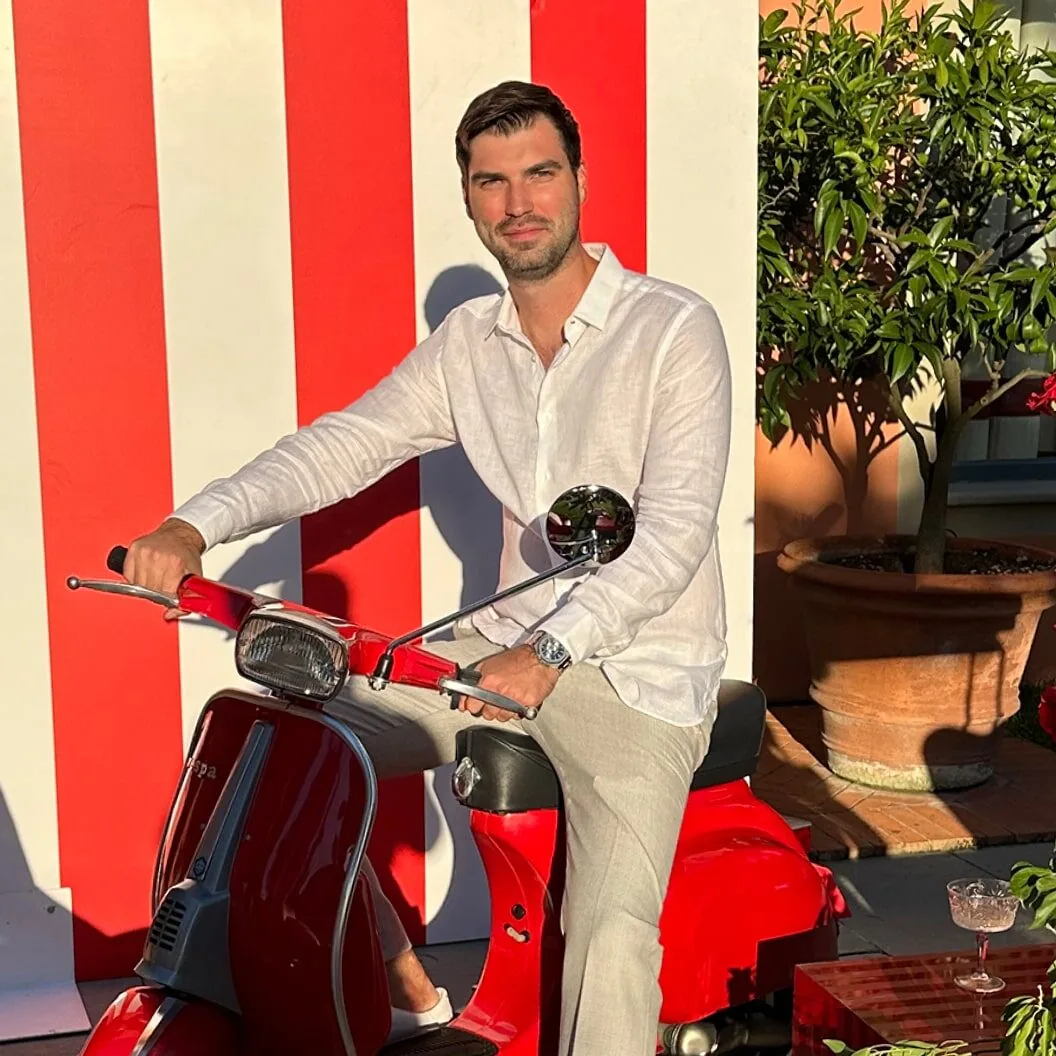 A man sitting on a red and white scooter.