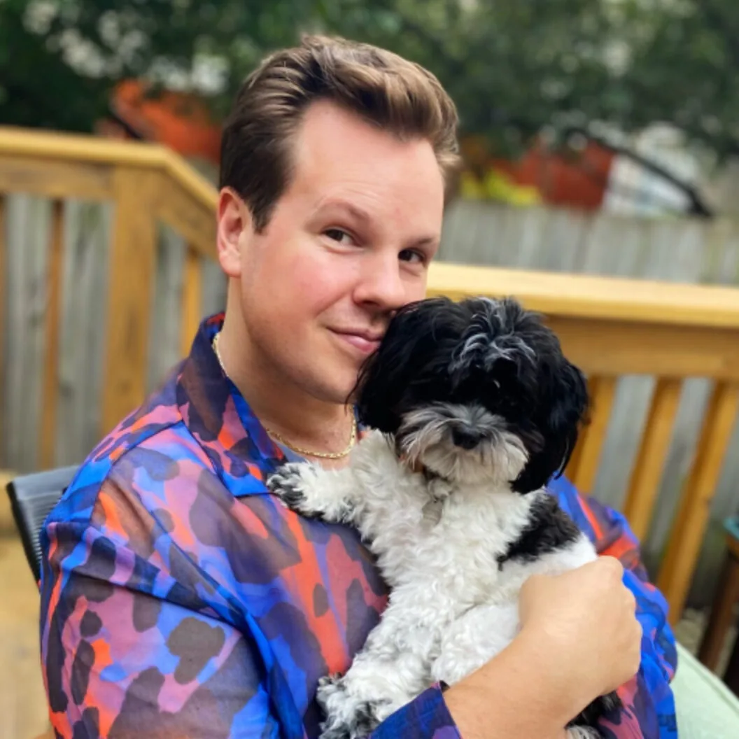 A man holding a black and white dog on a deck.