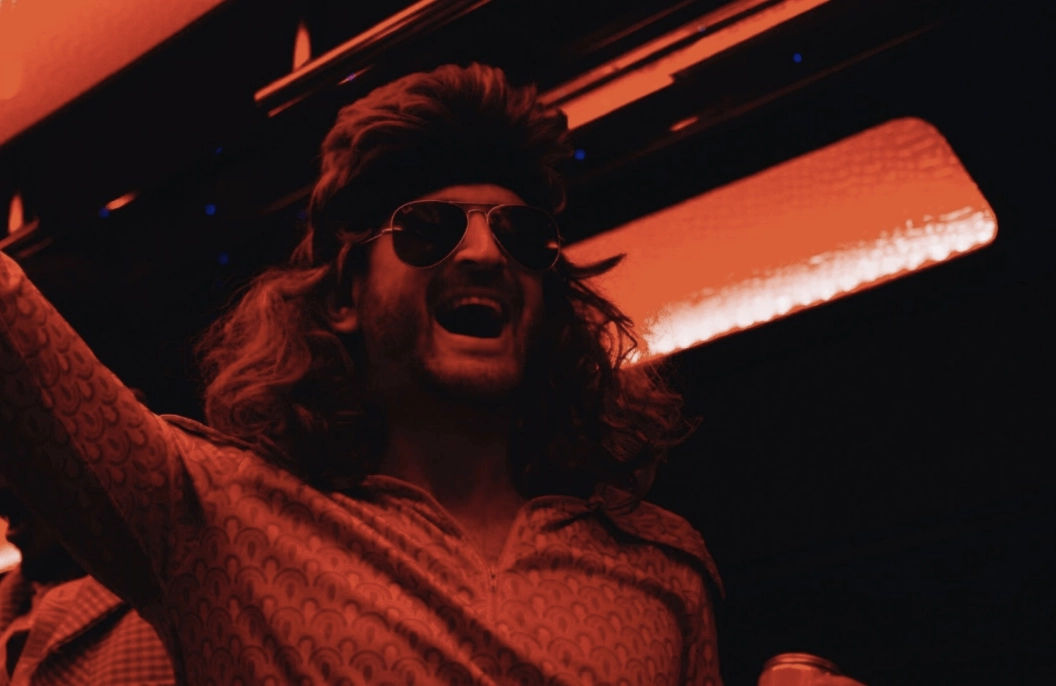 A man with long hair and glasses is on a bus.